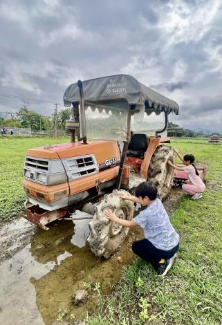 小朋友正在清理耕耘機大車輪的泥土