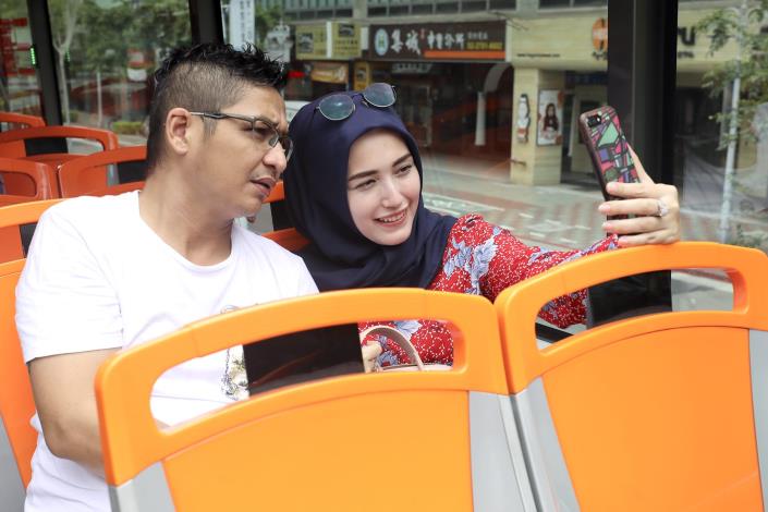 Pasha與太太搭乘雙層觀光巴士玩自拍，欣賞臺北街景。