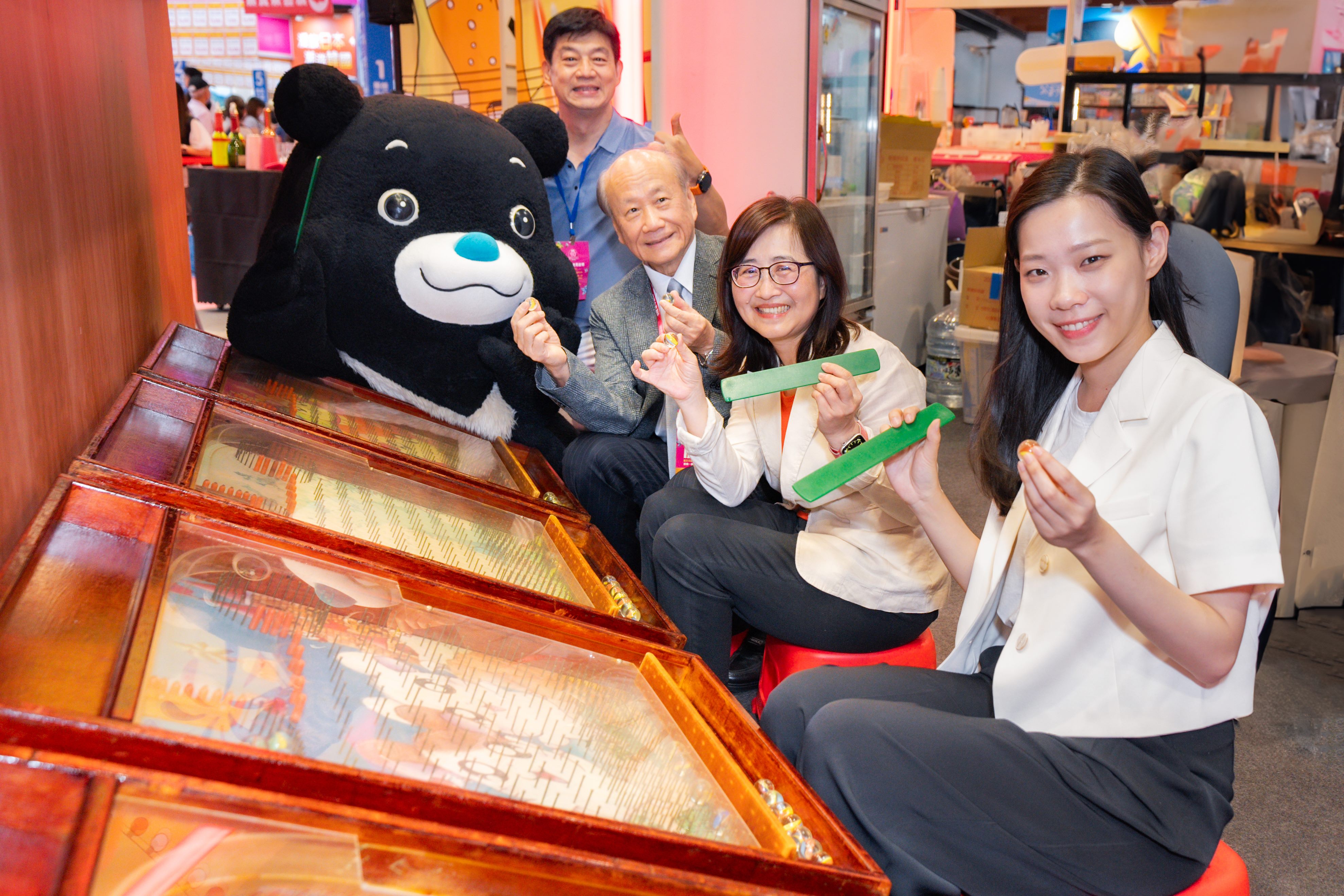 臺北市林奕華副市長（中）、觀傳局余祥局長（右）與台灣旅遊交流協會張家祝理事長（左），體驗「臺北館」復古夜市手撥彈珠遊戲。