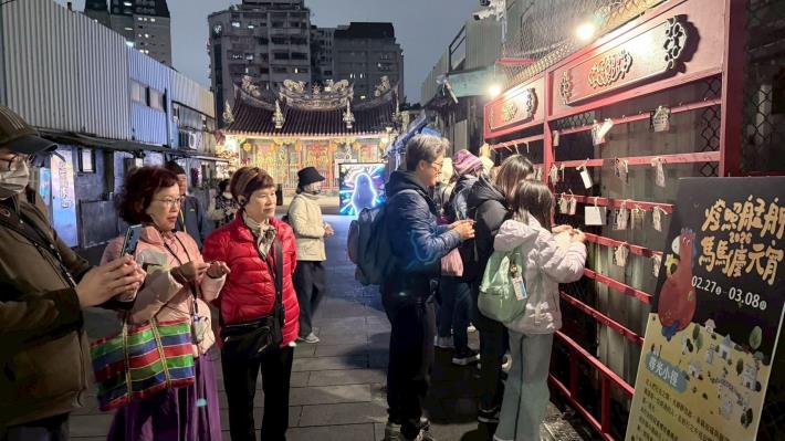 民眾在「燈照艋舺：馬馬慶元宵」活動許願牆綁上許願卡，祈求平安與心願成真。