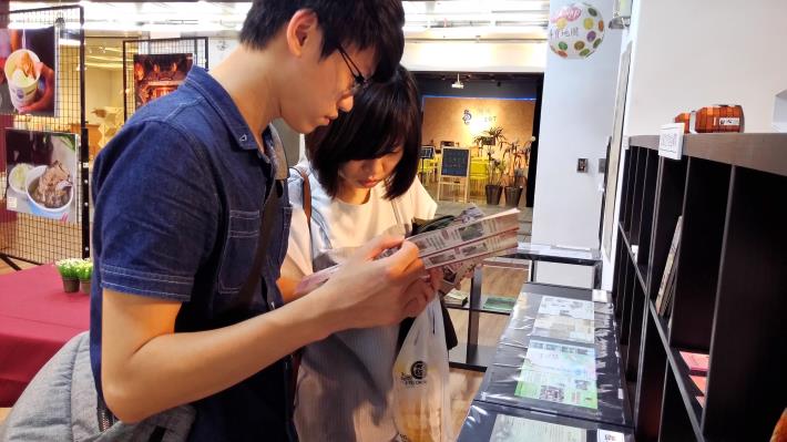 民眾於特展現場翻閱文宣品及旅遊導覽手冊