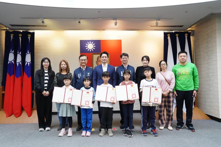 1141223_01(24)_表揚「參加健走趣的我們這一家」繪畫徵選獲選學童，請衛生局黃局長、教育局湯局長、全體中、低年級組獲獎學童及家長上臺一同合影。.JPG
