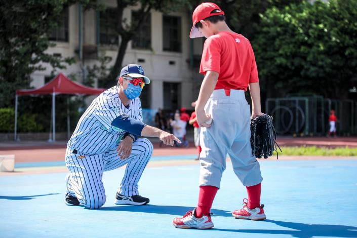 臺北興富發棒球隊球員蘇俊榮（左一）指導東園國小棒球員調整投球姿勢
