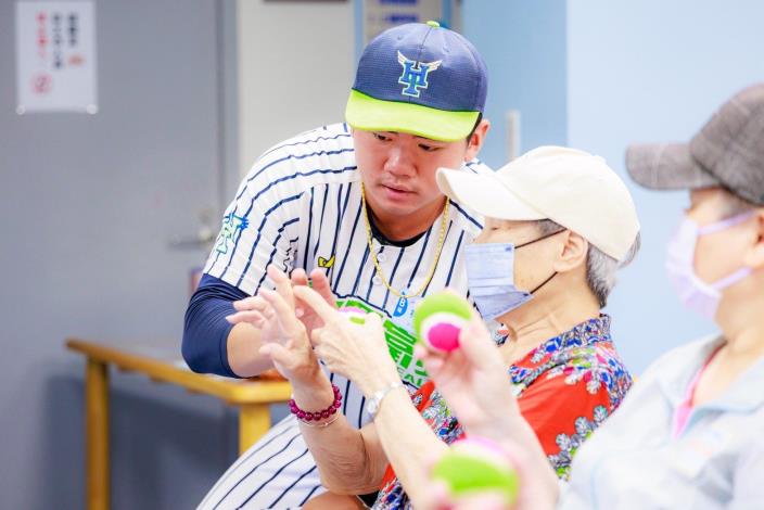 圖6臺北興富發棒球隊隊員仔細教導長者如何投球。