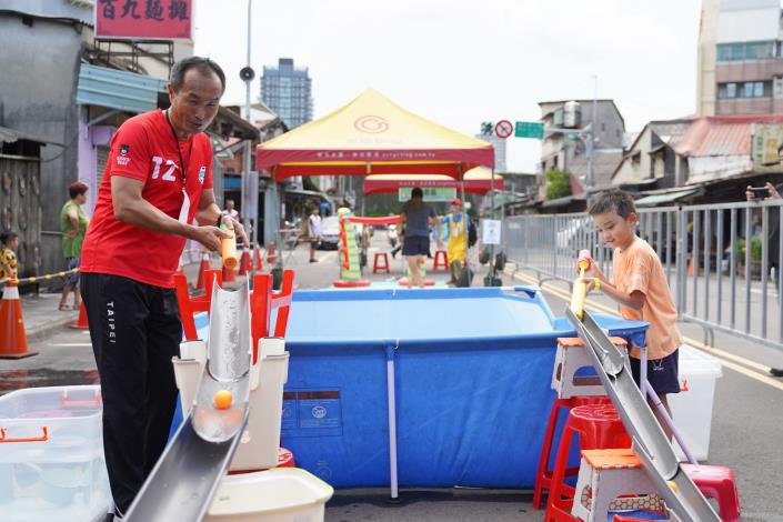 8月15日大同場次-本局李再立局長與孩童互動，用水槍射水道上的乒乓球，看誰先達陣!!