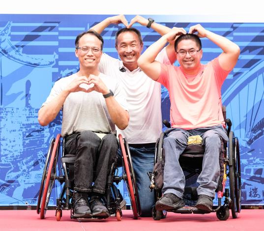 李再立局長和兩位身障輪椅運動選手呂豐和（左）、王偉軒（右）一起比愛心，象徵「愛運動，動無礙」推廣運動平權