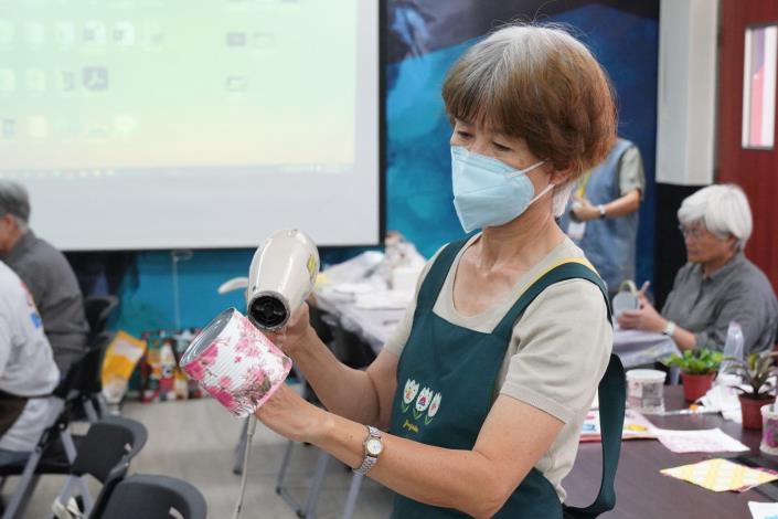 學員們挑選自己喜愛的布料或紙張，細心將圖案剪裁並裝飾在鐵製容器上。