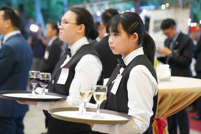 餐飲科學生於國慶晚宴現場執行餐飲服務,手持酒盤、神情專注,展現國際級宴會的專業訓練與穩健台風。.JPG