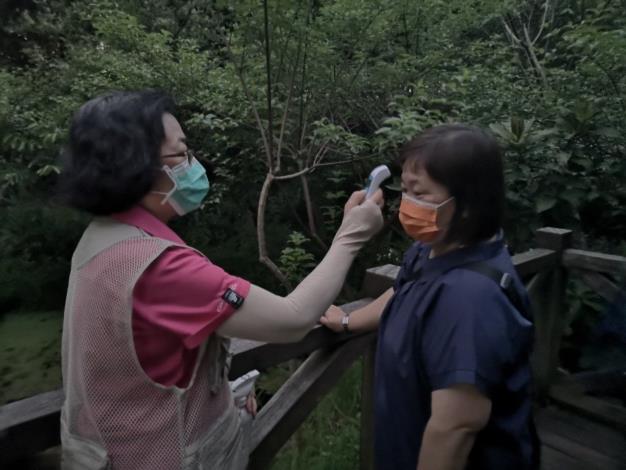 圖9防疫優先，值勤志工對賞螢民眾進行體溫量測及消毒手部等防疫措施。