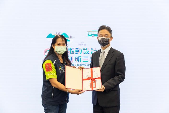 Commissioner Tom Chou of the Department of Civil Servant Development presenting a certificate of completion to Chief Chia-Nan Chan of Zhinan Village