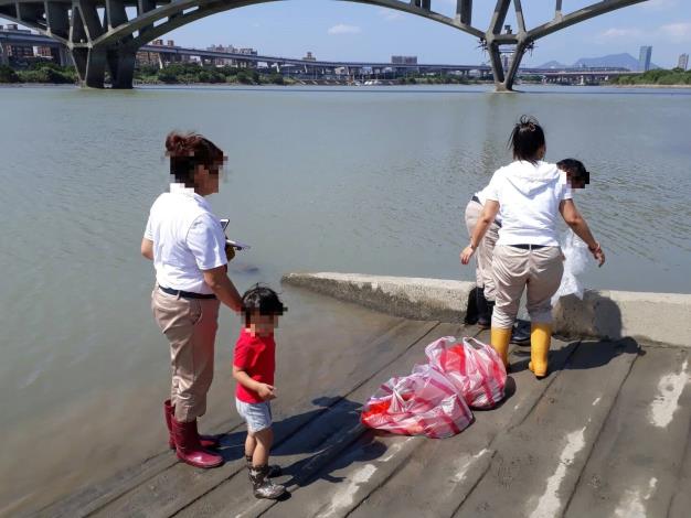 圖1.放生者一家以塑膠袋盛裝動物，準備於河濱公園放生。