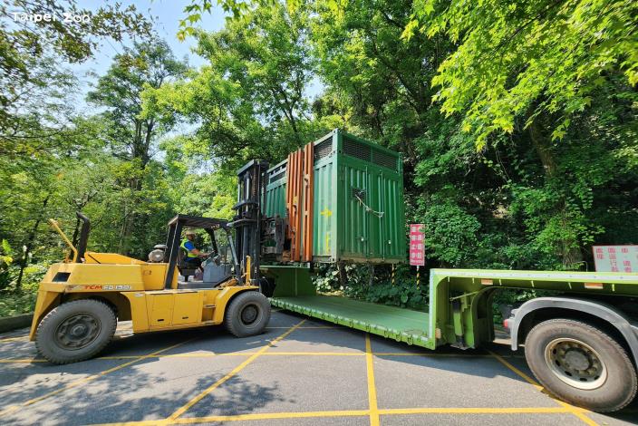 載著大象的貨櫃吊起後再由堆高機移動至低底盤拖車，以便前往非洲動物區。