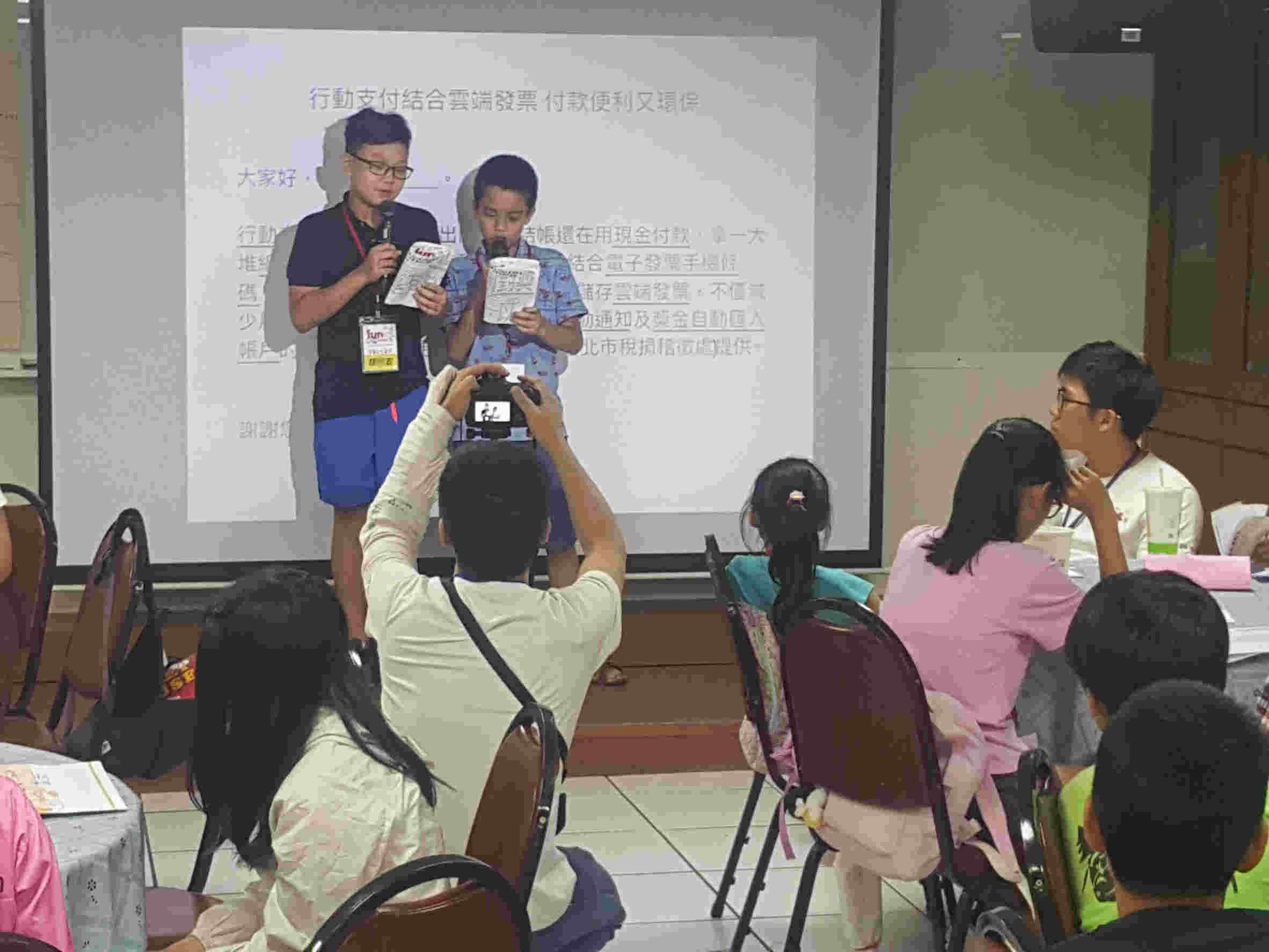 Boy and girl participants play broadcaster on stage