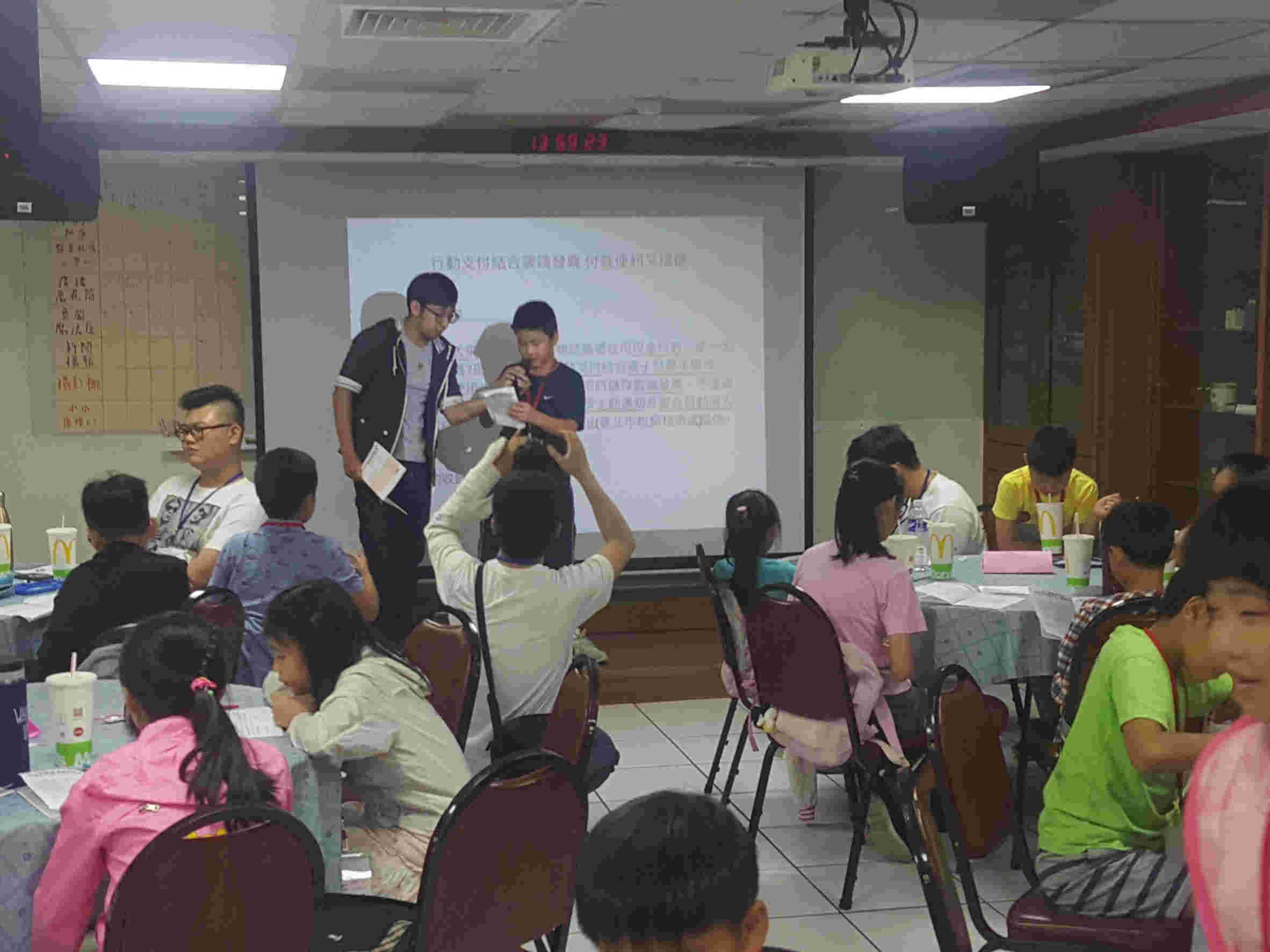 Boy and girl participants play broadcaster on stage