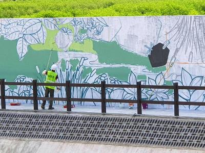 An artist working on the mural at the riverside