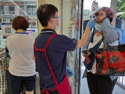 Supermarket staff taking the temperature of visitors