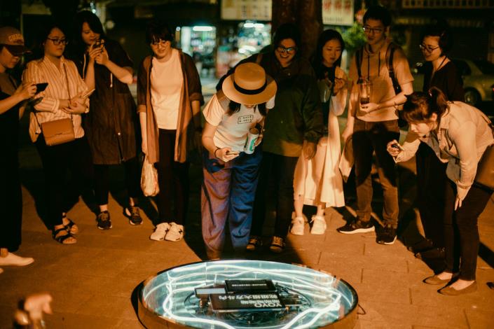 民眾在建成公園圍觀體驗由數位詩人MUSE化身的裝置藝術「鏡中謬思」。