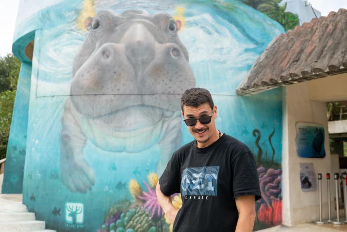 Graffiti artist ORBITA takes a photo with his hippo mural.