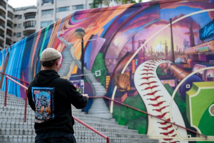 Graffiti artist FLEKS takes a photo with his artwork at Tianmu Baseball Stadium.
