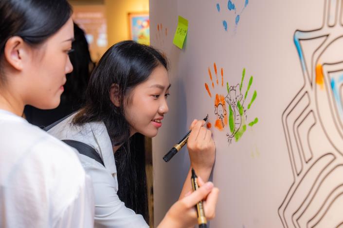 Interns draw a mandala on the message wall at the exhibition