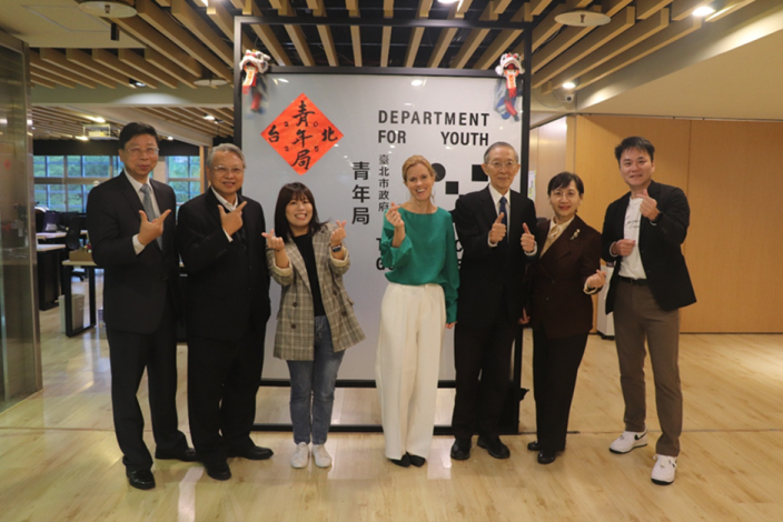 Picture 6: Ms. Ruth Bradley-Jones, distinguished guests take a group photo with the Department for Youth logo backdrop.