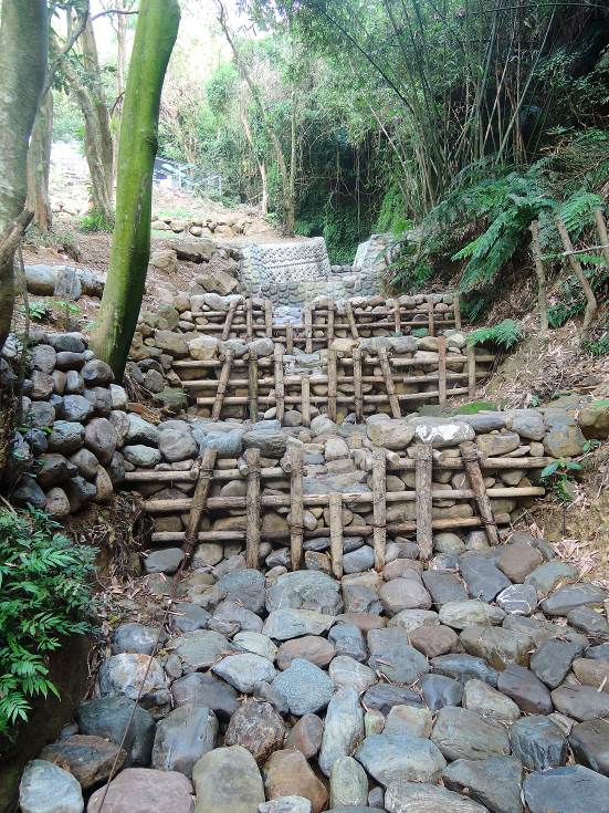 以生態工法(木樁節制工)進行土石流潛勢溪流整治，以「輕量」的概念進行治理