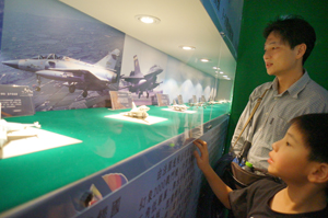 A young child looks attentively at the fighter jet models.