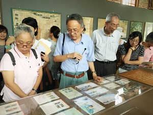The 73-year-old historian Chuang Yung-ming holds a mini microphone, guiding visitors through his private collection. (Photo courtesy of Taipei City Archives Committee)