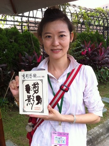 Wendy Ma poses for a photo holding the book about silhouette cutting written by her father, Oct. 22 in Taipei Water Park while participating in the 2011 Taipei Street Artists Carnival. (Photo courtesy of Wendy Ma)