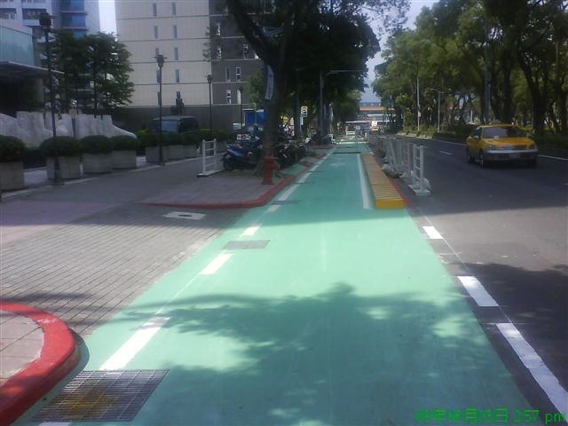 Colored pavement extends to the parking entrance; dotted lines are added to indicate that cars and motorcycles are allowed crossing here. Vehicles of various kinds have to beware of each other; drivers need to slow down when making turns 