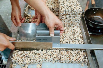 After pressing, the warm cakes will be cool and set. They are then cut into smaller pieces to be packaged and sold.