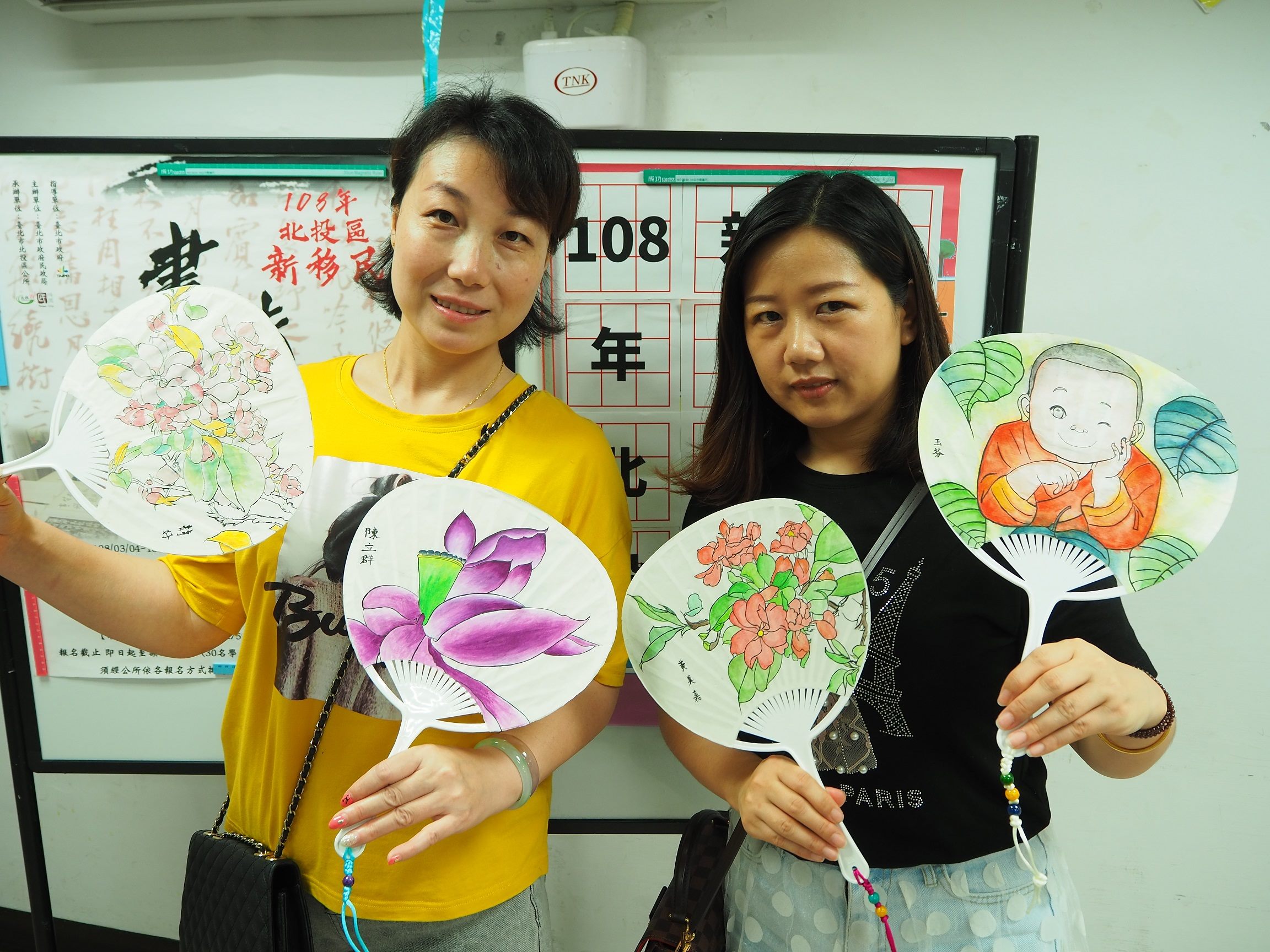 Students posing with their works on paper fans