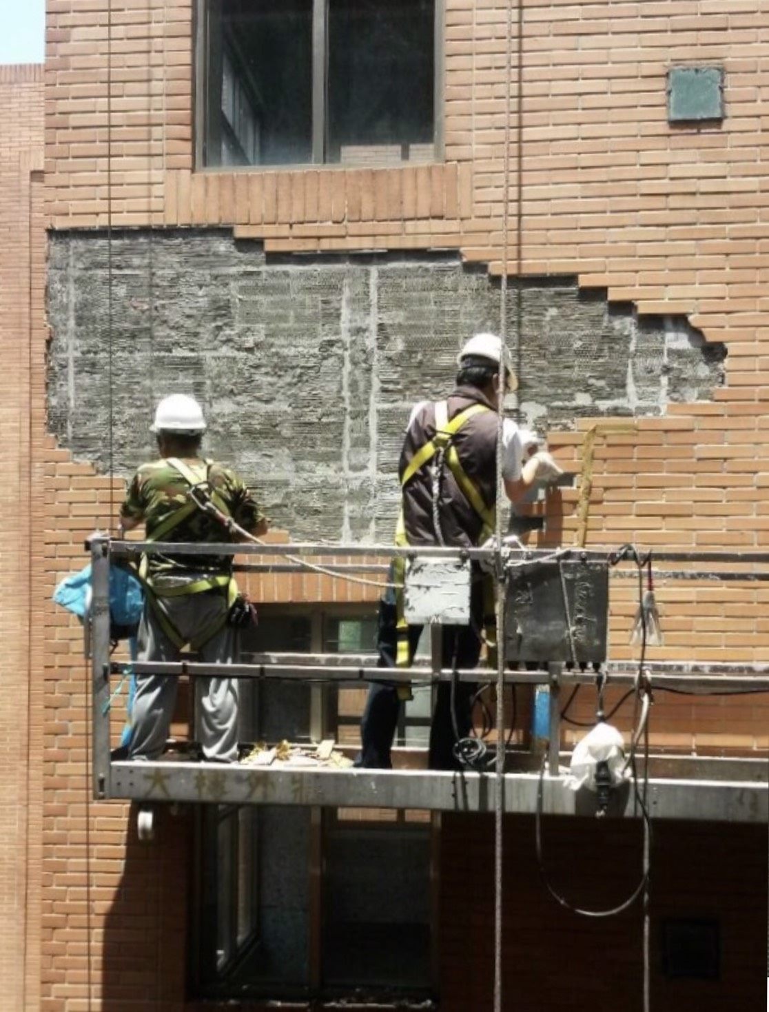 Workers repairing damaged building wall surfaces